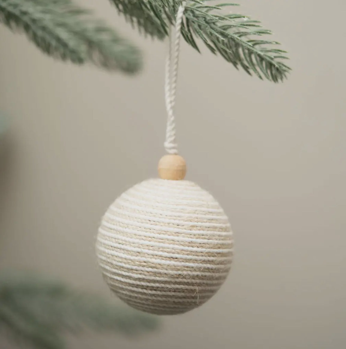 Textured round ornament hanging from a branch with a blurred background