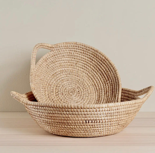 Woven basket with a lid on a light wooden surface against a neutral background