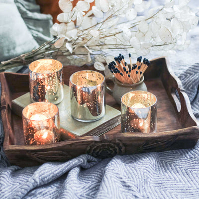 Decorative setting with lit candles in Silver Antique Effect Tea-Light Holders on a wooden tray.