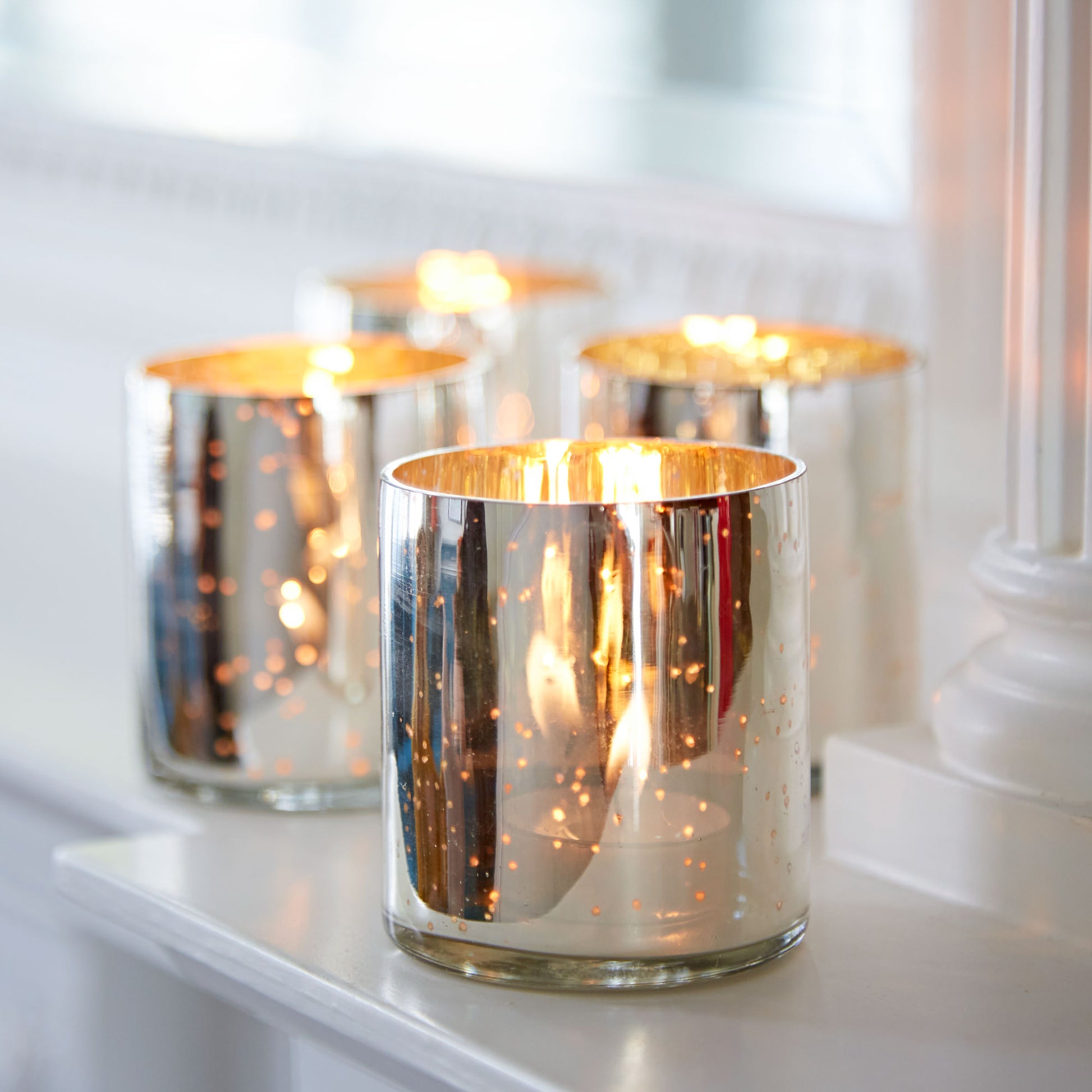 Silver Antique Effect Tea-Light Holders with candles on a white surface