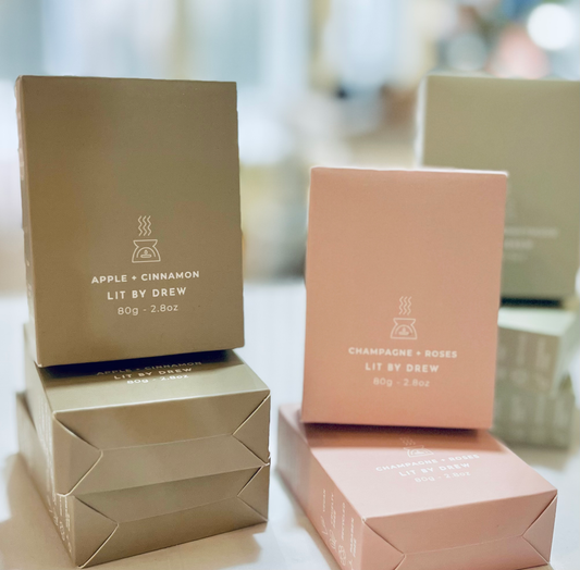 Three boxes of Lit by Drew products on a blurred background