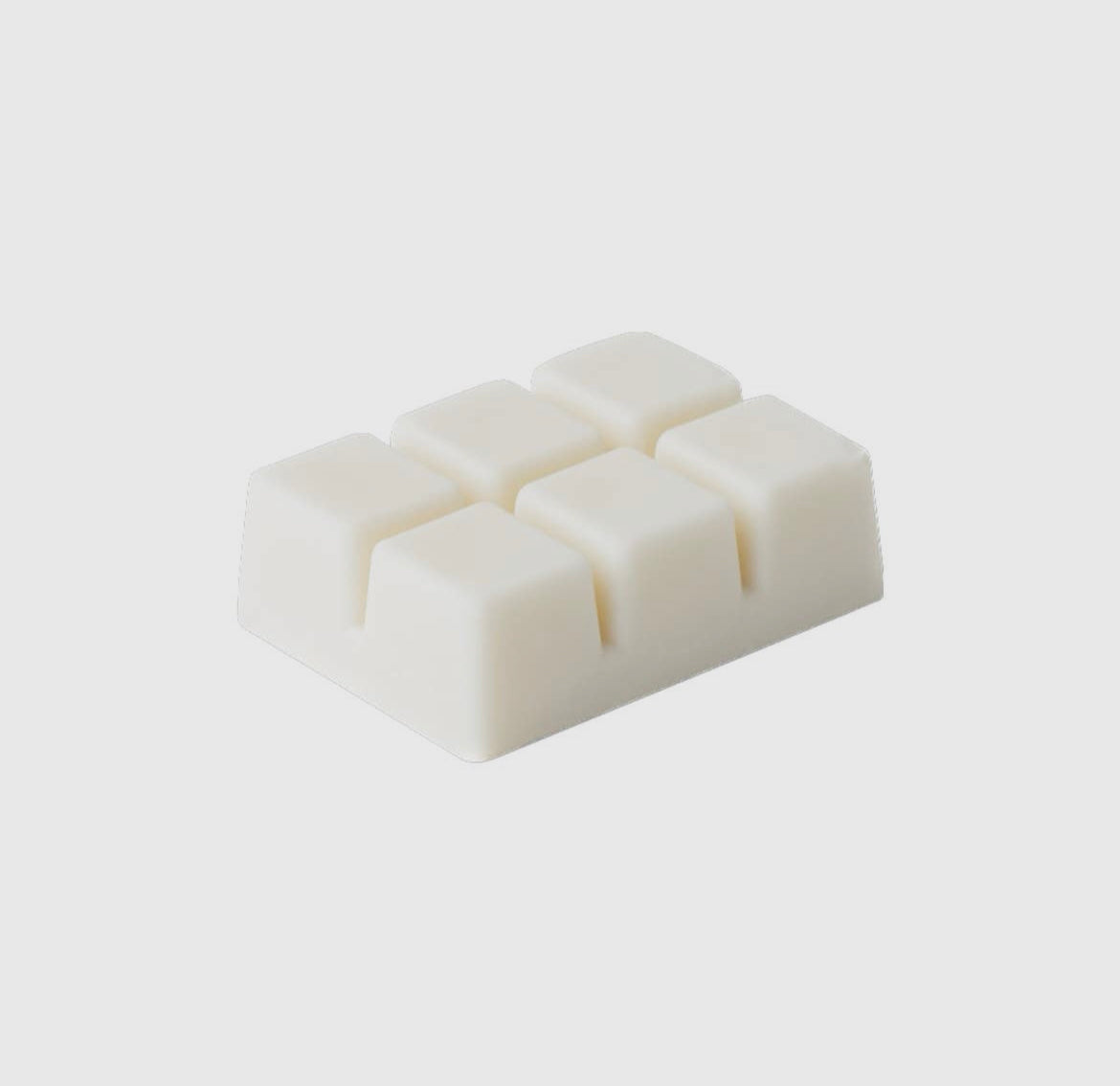 Rectangular block of white wax with four square pieces on a light gray background