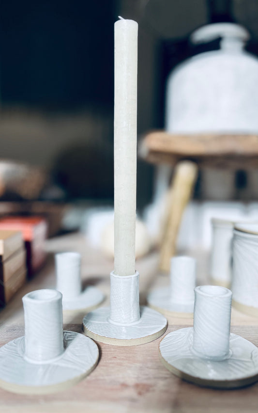 White candle on a decorative Stoneware Clay Candle Holder with blurred background