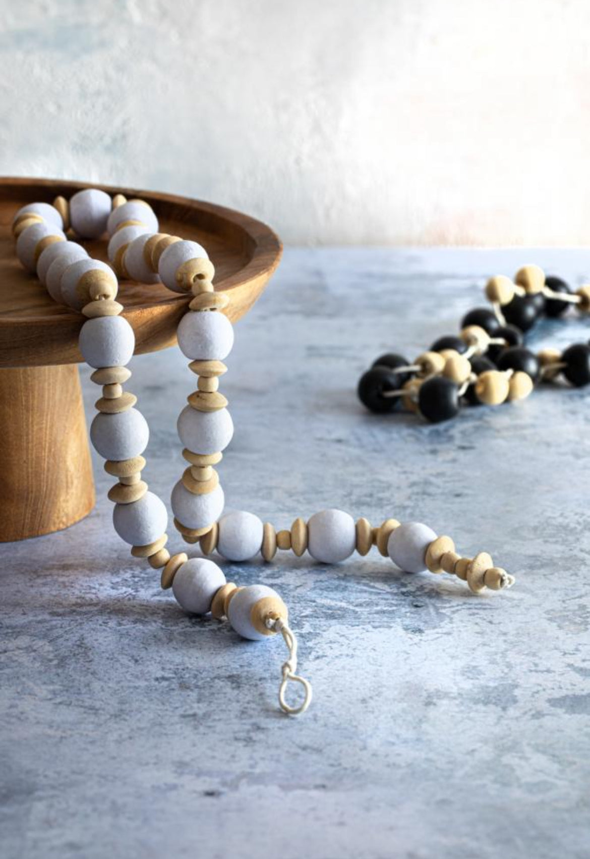 Wooden beaded necklace on a textured surface with a neutral background