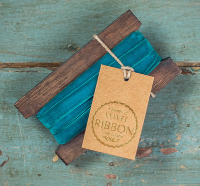 Teal velvet ribbon with wooden clips on a rustic wooden surface, featuring a 'Velvet Ribbon' tag.