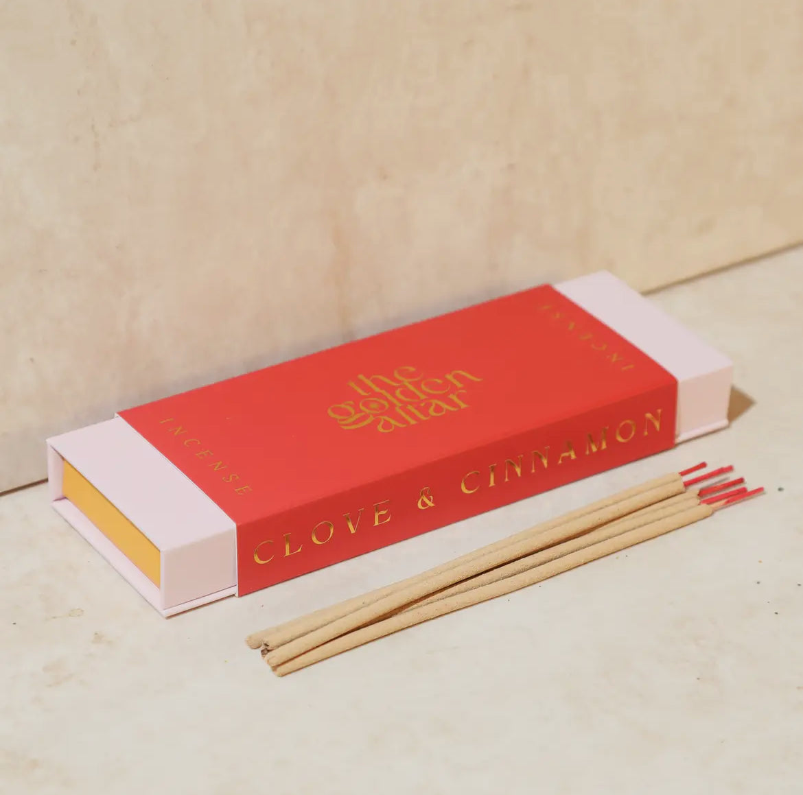 Incense sticks with a red box labeled 'Clove & Cinnamon' on a beige background