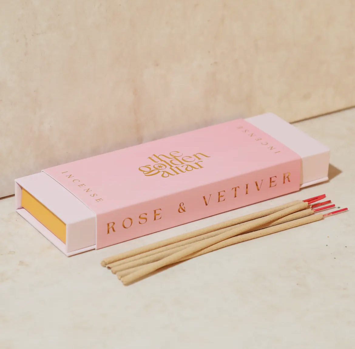 Incense sticks with a pink box labeled 'Rose & Vetiver' on a beige background