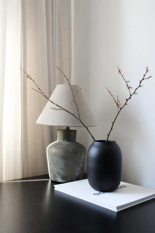 Two vases with branches on a table against a neutral background