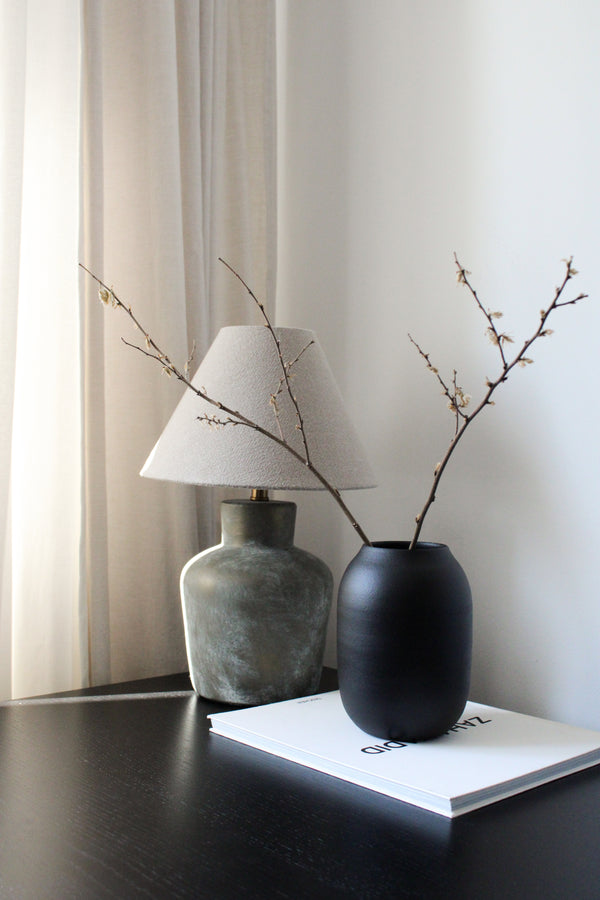 Two vases with branches on a table against a neutral background