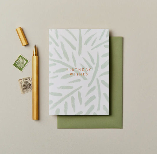 Greeting card with 'Birthday Wishes' text, green envelope, pen, and stamps on a beige background