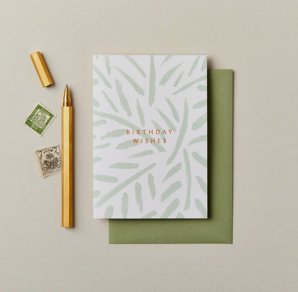 Greeting card with 'Birthday Wishes' text, green envelope, pen, and stamps on a beige background