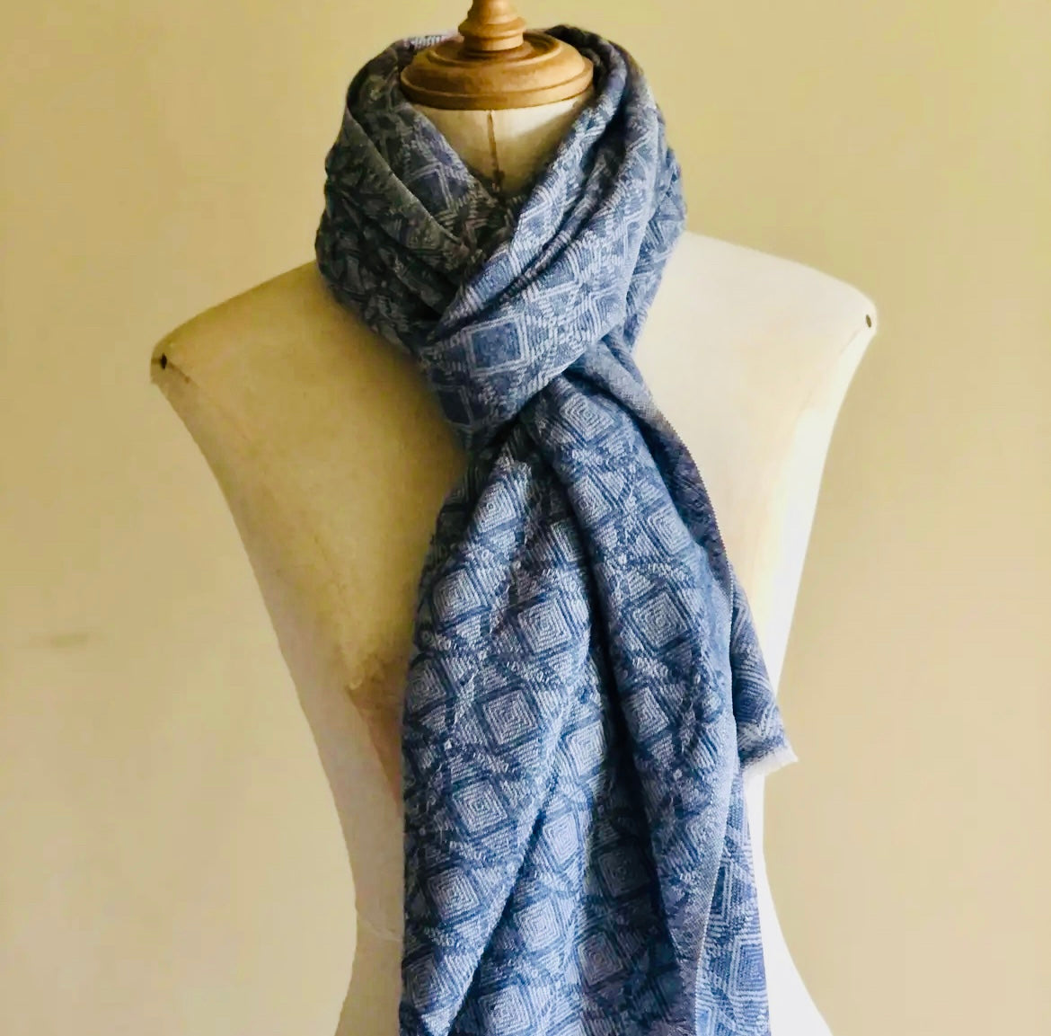 Blue patterned scarf on a mannequin against a beige background