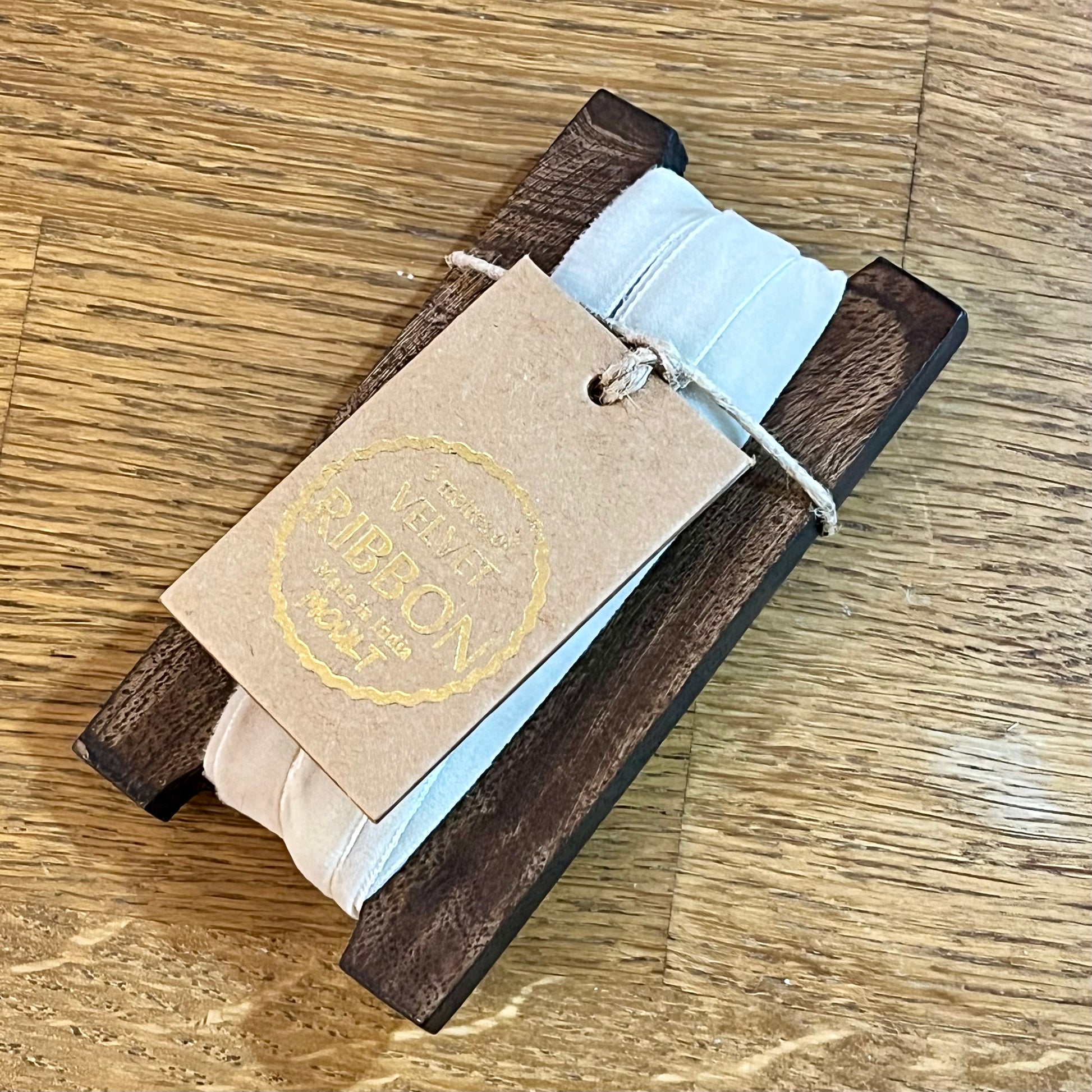 Wooden product with a light blue strap and a branded tag on a wooden surface